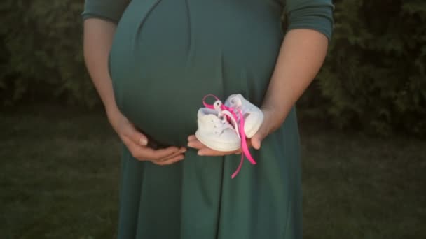 Imagen de mujer embarazada con pequeños zapatos de bebé en la mano — Vídeos de Stock