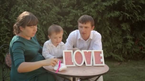 Familia joven sentada en una mesa con un signo de amor — Vídeo de stock