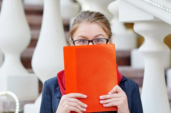 Frau mit Brille bedeckt ihr Gesicht mit roter Mappe — Stockfoto