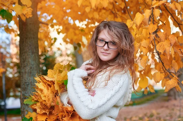 Young woman in sunglasses walking in autumn park — Stock Photo, Image