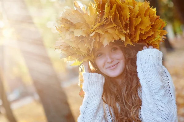 Happy young woman with a wreath of yellow leaves walking in the park — Stock Photo, Image