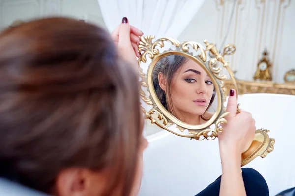 Hermosa mujer en el baño mirando en el espejo — Foto de Stock