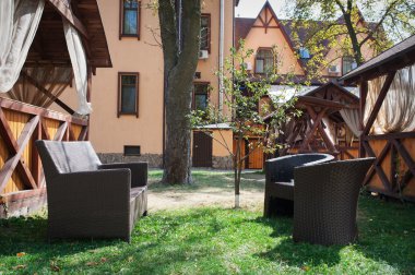 kahverengi deri kanepe ve evin yanında bahçesinde iki sandalye