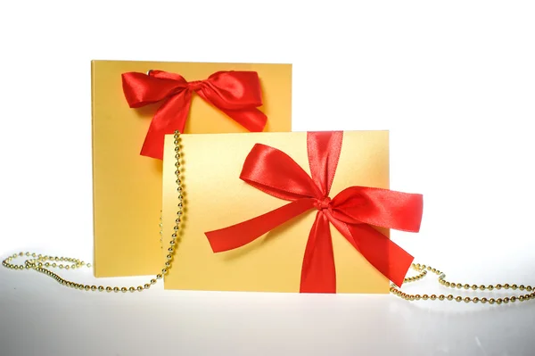 Golden gift wrapped present with red satin ribbon bow on white — Stock Photo, Image