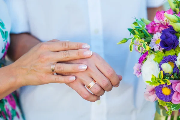 Mãos de noiva e noivo com anéis e buquê de casamento — Fotografia de Stock