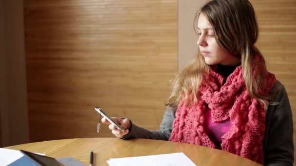 Büroangestellte sitzt an ihrem Arbeitstisch und schreibt mit ihrem Handy SMS — Stockvideo