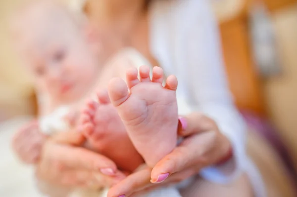 Glückliche junge Mutter hält kleine Füße ihres Sohnes — Stockfoto