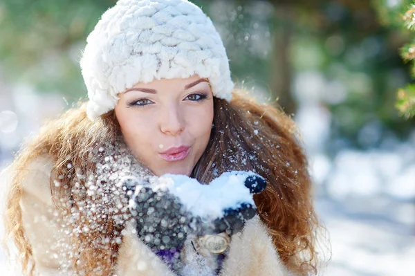 Bella donna in inverno soffia neve con le mani — Foto Stock