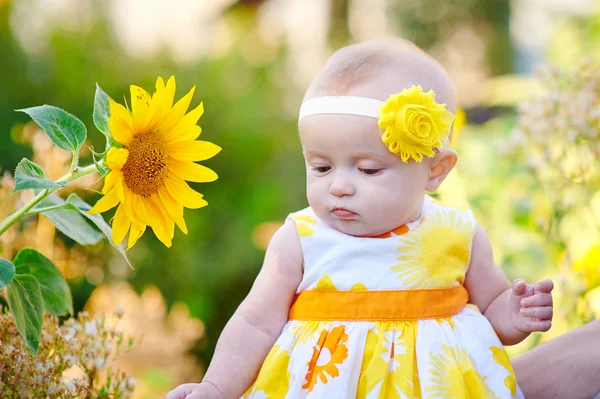 Beautiful baby girl near yellow sunflowers on field — Stock Photo, Image