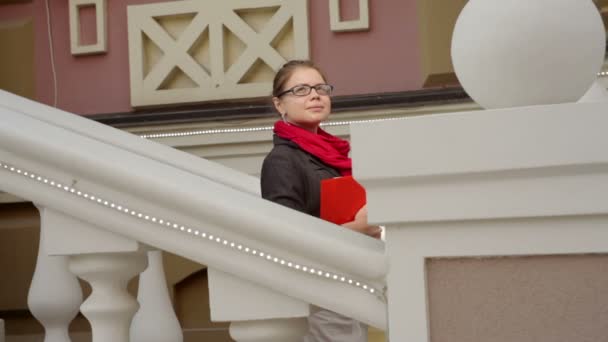 Schöne Frau steht an einer Steinmauer gegen die Treppe — Stockvideo