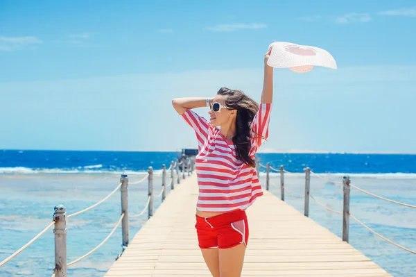 Happy woman standing on pier with big white hat — Stock Photo, Image
