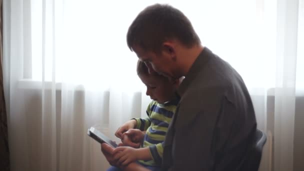 Dad and son watching pictures and videos in the smartphone — Stock Video