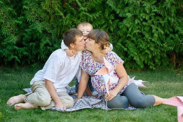 Familia de madre padre e hijo, padres besándose y niñito sonriendo y abrazándose — Foto de Stock