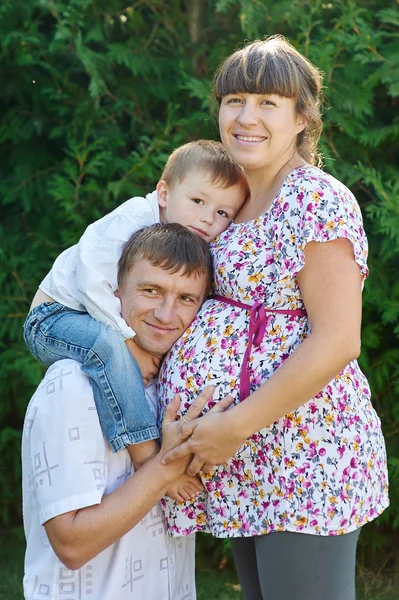 Счастливая семья. Беременная мать с мужем и сыном в парке — стоковое фото