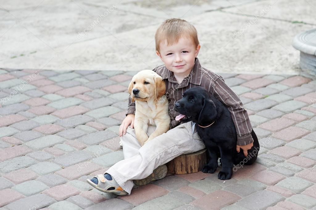 Niños jugando con dos perros labrador blanco y negro — Foto de