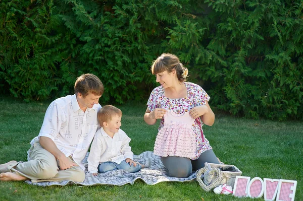 Jeune famille assise sur l'herbe dans un parc d'été avec lettres amour — Photo