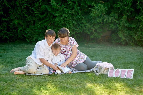 family sitting on the grass in a park with letters love and read book