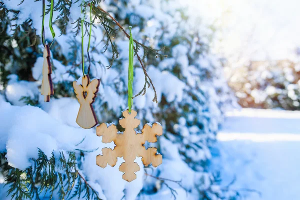 Brinquedos de madeira pendurar em uma árvore de Natal coberta de neve no parque no inverno — Fotografia de Stock