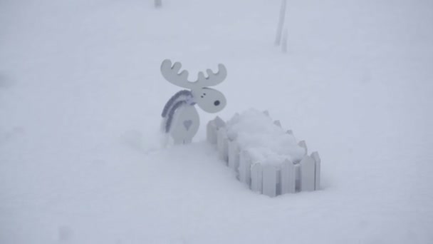 Trä leksak älg och ett litet staket i snön — Stockvideo