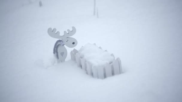 Trä leksak älg och ett litet staket i snön — Stockvideo