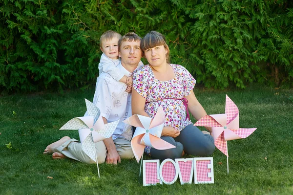 Mladá rodina s piknik s větrnými mlýny na trávě — Stock fotografie