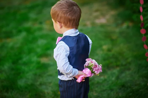 小男孩抱着一束鲜花在他的背后 — 图库照片