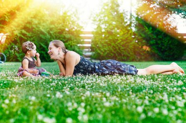Anne ve küçük kızı piknik bir parkta çimlere oturup