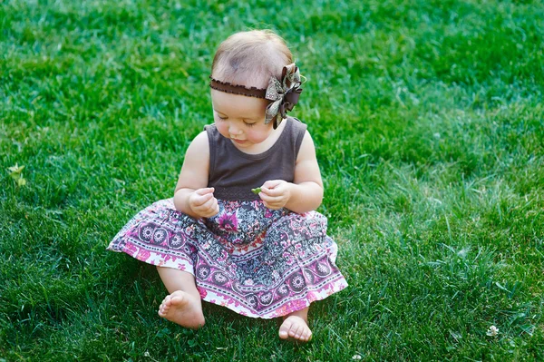 Χαριτωμένο μικρό κορίτσι, συνεδρίαση για το γρασίδι μια ηλιόλουστη καλοκαιρινή μέρα — Φωτογραφία Αρχείου