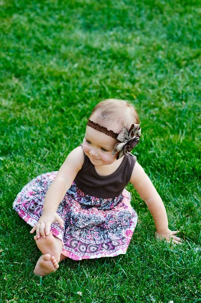Cute dziewczynka siedzi na trawie w słoneczny letni dzień — Zdjęcie stockowe