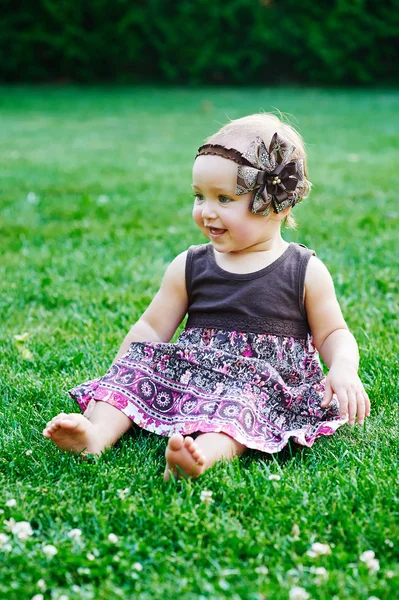 可爱的小女孩坐在草地上，在阳光明媚的夏日 — 图库照片