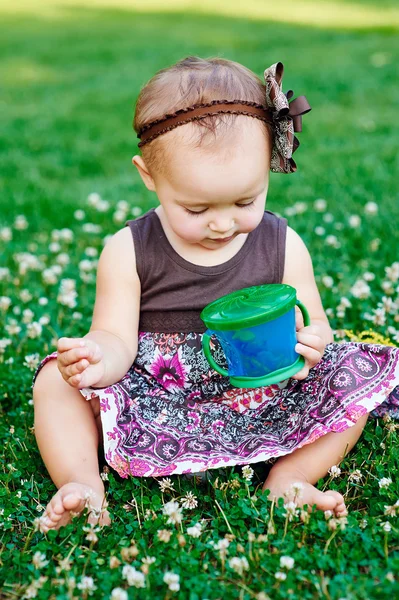 Kleines Mädchen sitzt auf dem Gras und isst Süßigkeiten — Stockfoto