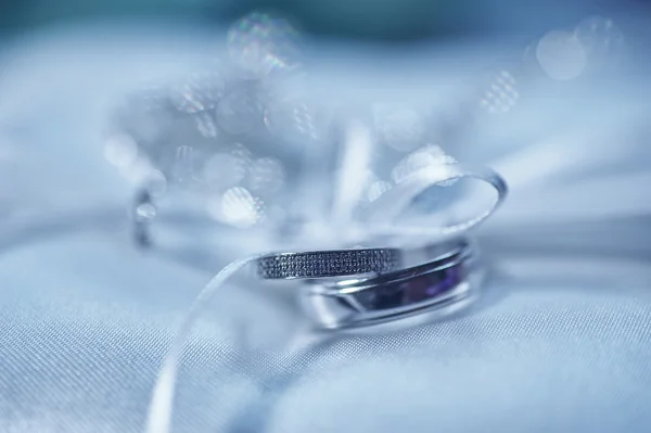 Красивые обручальные кольца на подушке с лентой в голубых тонах — стоковое фото