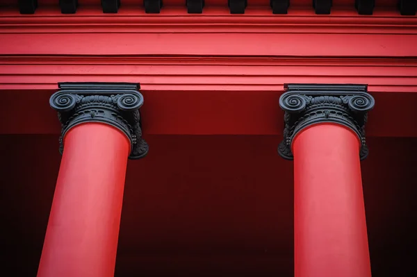 Detalhes de duas belas colunas vermelhas que suportam o telhado do antigo edifício vermelho — Fotografia de Stock