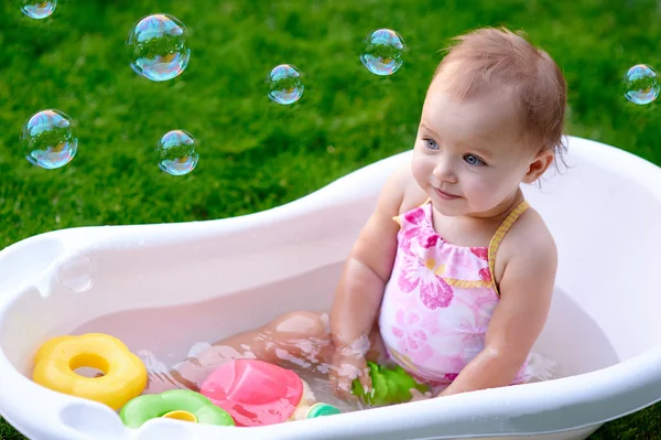 Красивая маленькая девочка летом купается с мыльными пузырями — стоковое фото