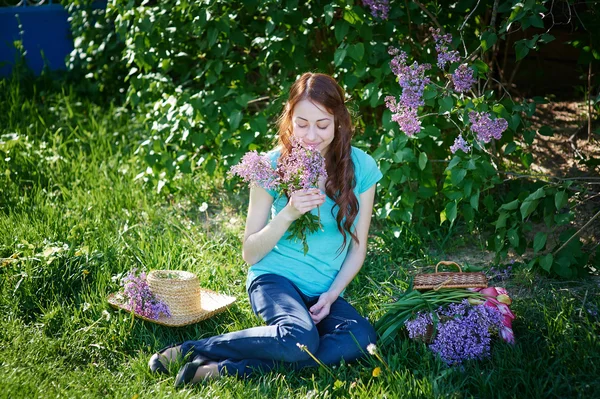 Krásná žena, sedící na trávě v parku na jaře — Stock fotografie