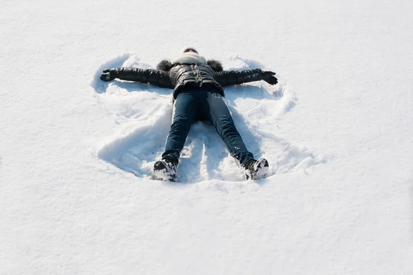 Menina na neve fazendo anjo — Fotografia de Stock