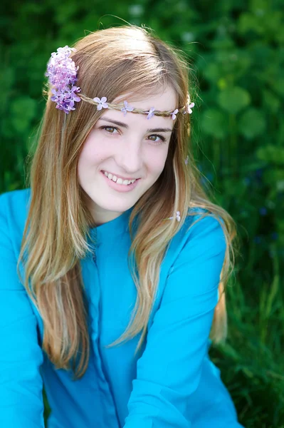 Retrato de una hermosa joven con una corona en el parque de primavera — Foto de Stock