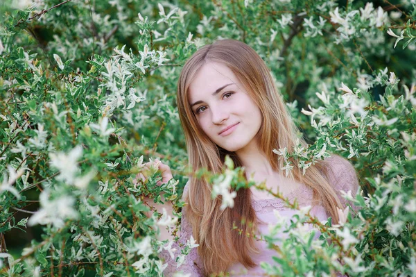 Schöne junge Frau, die in einem blühenden Frühlingsgarten spaziert — Stockfoto