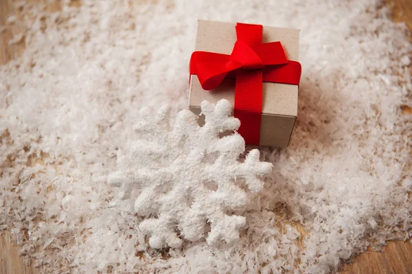 Christmas gift kraft paper and a snowflake in the snow — Stock Photo, Image