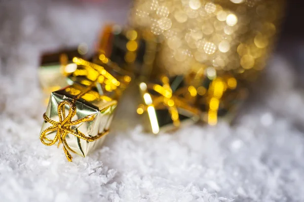 Christmas present in gold wrapping with ribbon on winter background — Stock Photo, Image