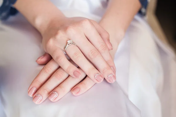 Bruden hand med manikyr på bröllopsklänning — Stockfoto