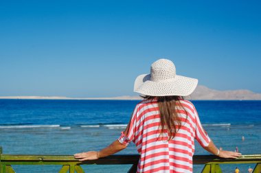 Beyaz şapka korkuluk ve görünüyor yanında deniz duran kadın