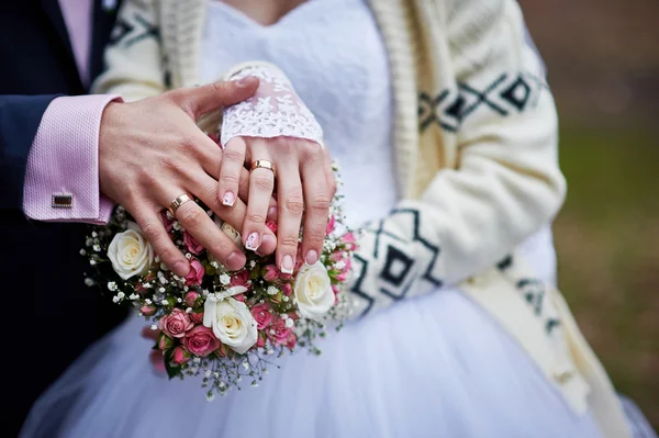 Ruce nevěsty a ženicha s kroužky na krásné svatební kytice — Stock fotografie