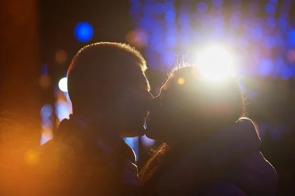 Happy couple kissing on the background of illuminations and bokeh — Stock Photo, Image