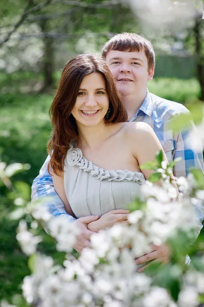 Ungt par poserar i blommande våren trädgård — Stockfoto