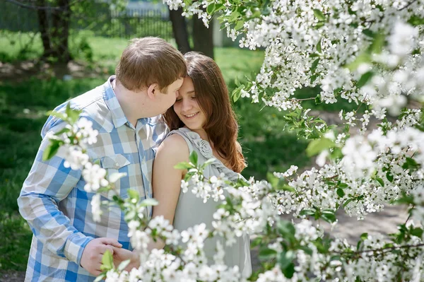 Pareja joven en el amor caminando en el jardín de primavera de flor — Foto de Stock