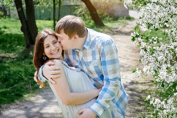 Uomo baciare una donna nel parco primaverile fiorito ciliegio — Foto Stock