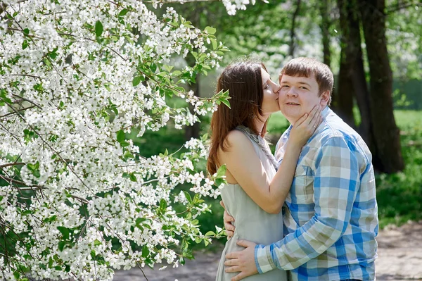 Mujer besando a un hombre en el floreciente jardín de primavera — Foto de Stock