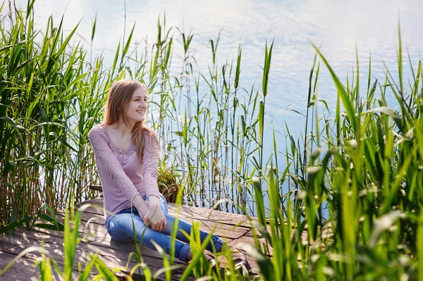 호수에 부두에 앉아 아름 다운 여자 — 스톡 사진