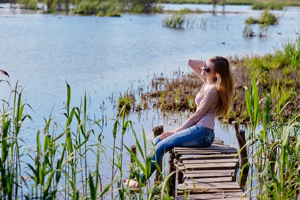 Bella donna seduta su un molo al lago — Foto Stock